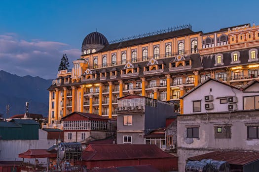 Stunning view of an ornate building facade lit during twilight with mountain backdrop.