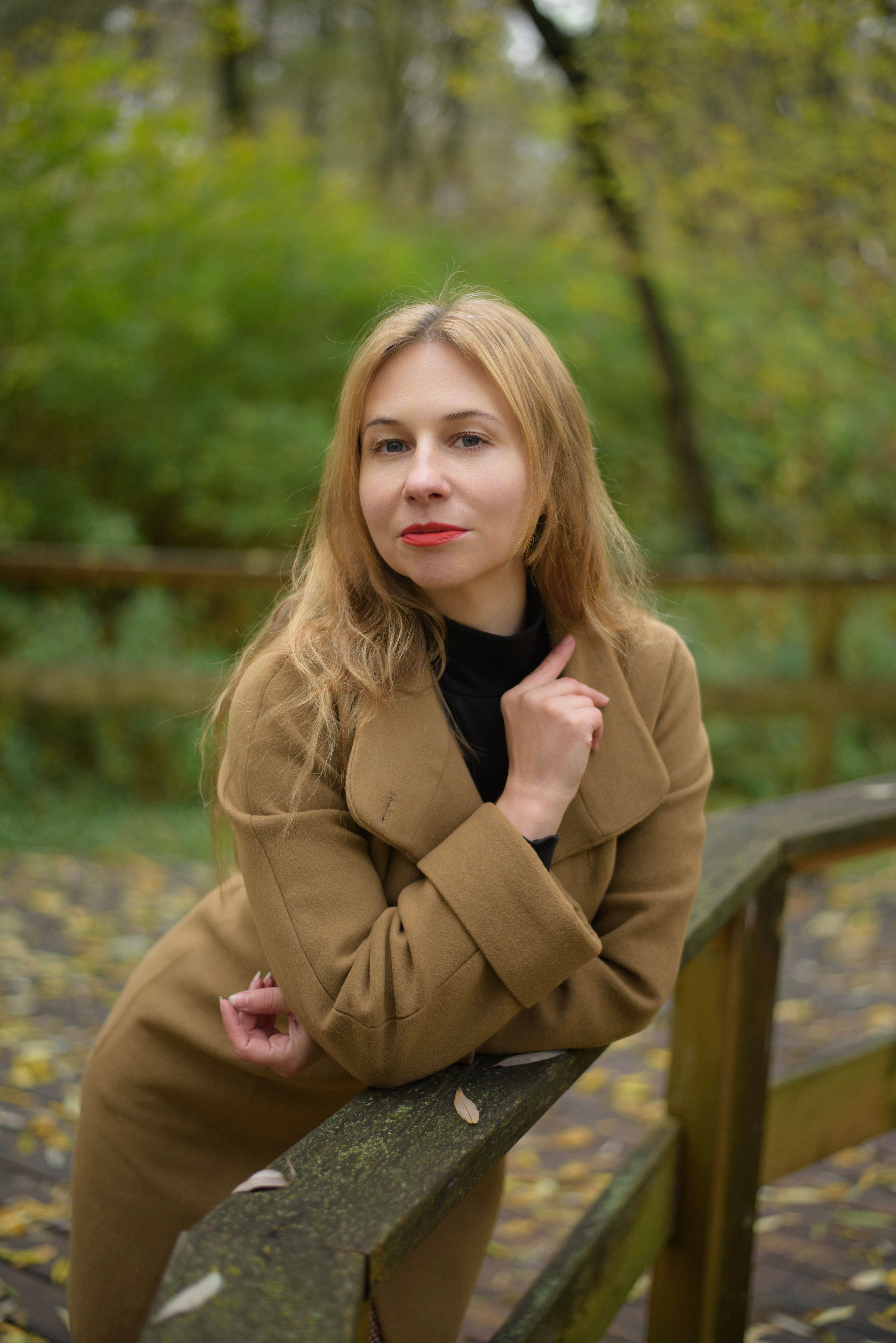 Woman in Autumn Coat Posing Outdoors on Wooden Bridge · Free Stock Photo