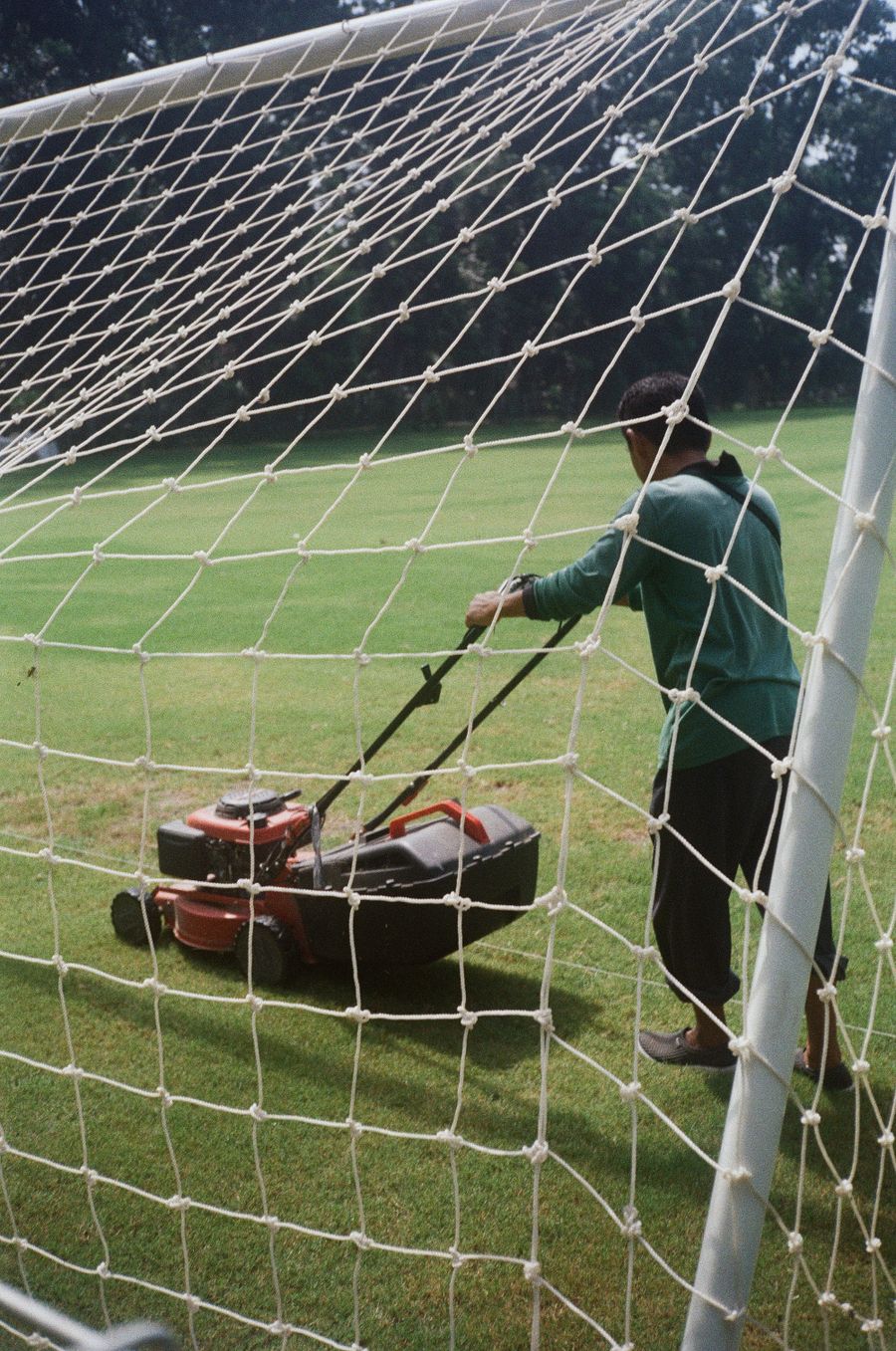 Groundskeeper mowing an open expanse of green turf