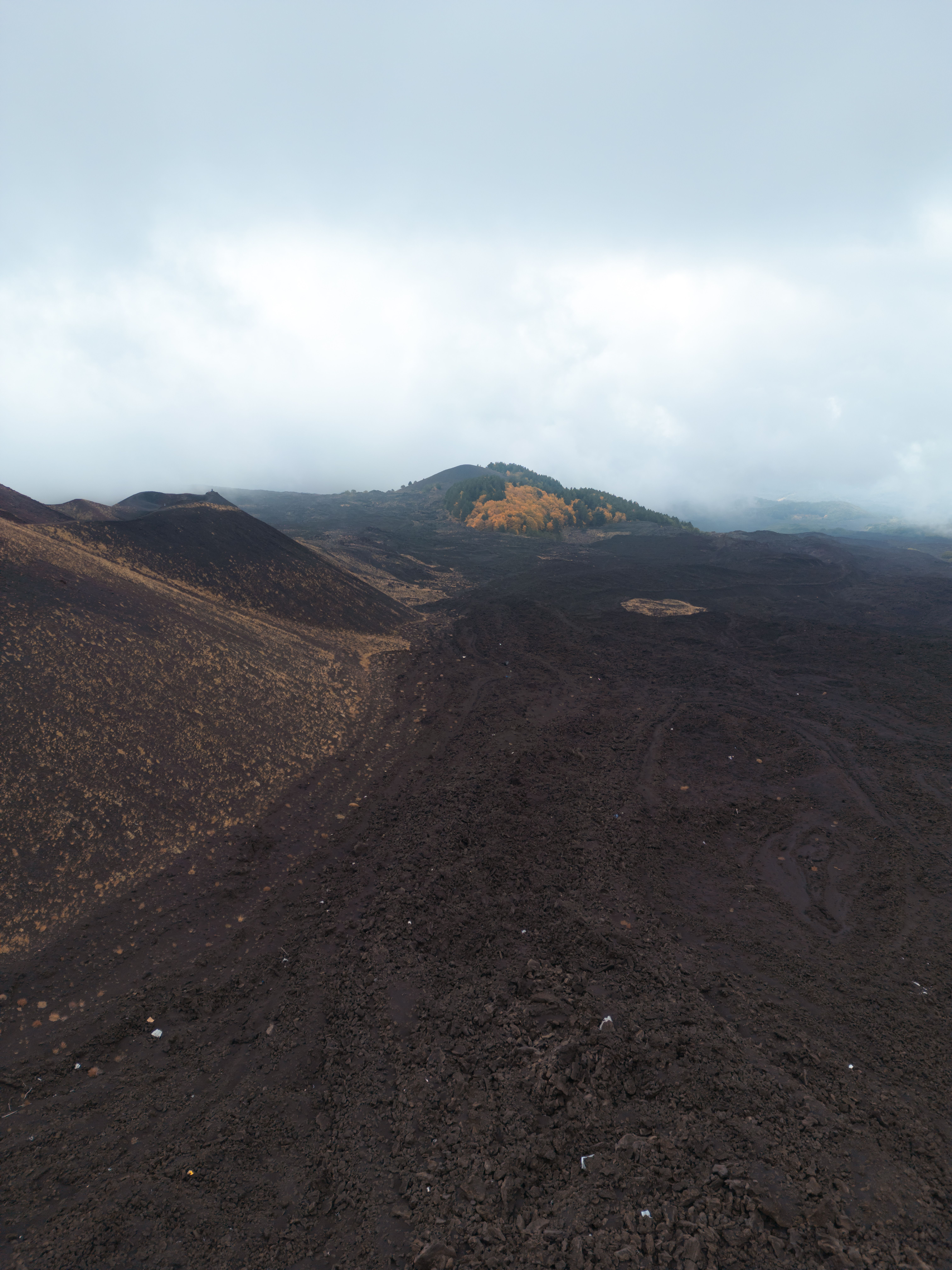 Vast volcanic landscape in Sicily showcasing rugged terrain and hills under a cloudy sky.