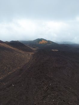 Vast volcanic landscape in Sicily showcasing rugged terrain and hills under a cloudy sky.