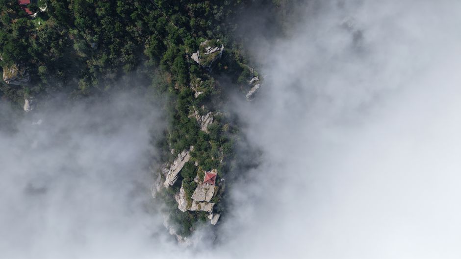 Best Guilin Yangshuo Helicopter and Sightseeing Private Day Tour Review 2026 - Aerial view of Lushan Mountain in mist, showcasing lush greenery and rocks surrounded by clouds.