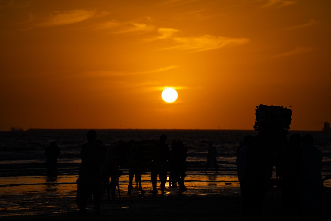 Silhouettes and camels against a sunset at Karachi beach