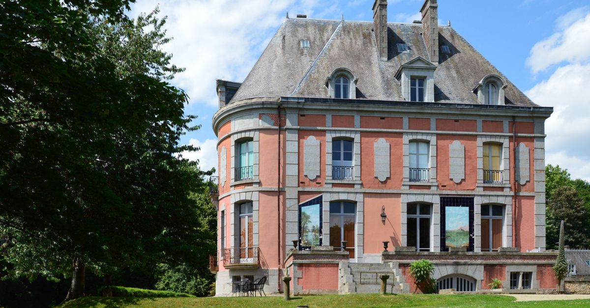 Beautiful historic red brick mansion in Bacilly, Normandie, framed by lush greenery.