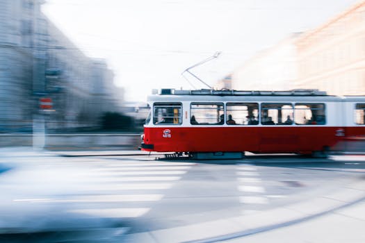 A red tram swiftly moves through the urban landscape of Vienna, showcasing dynamic city movement.