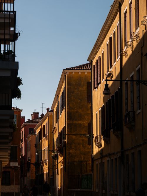 Free Charming sunlit street in Venice featuring warm-toned buildings and classic architecture. Stock Photo