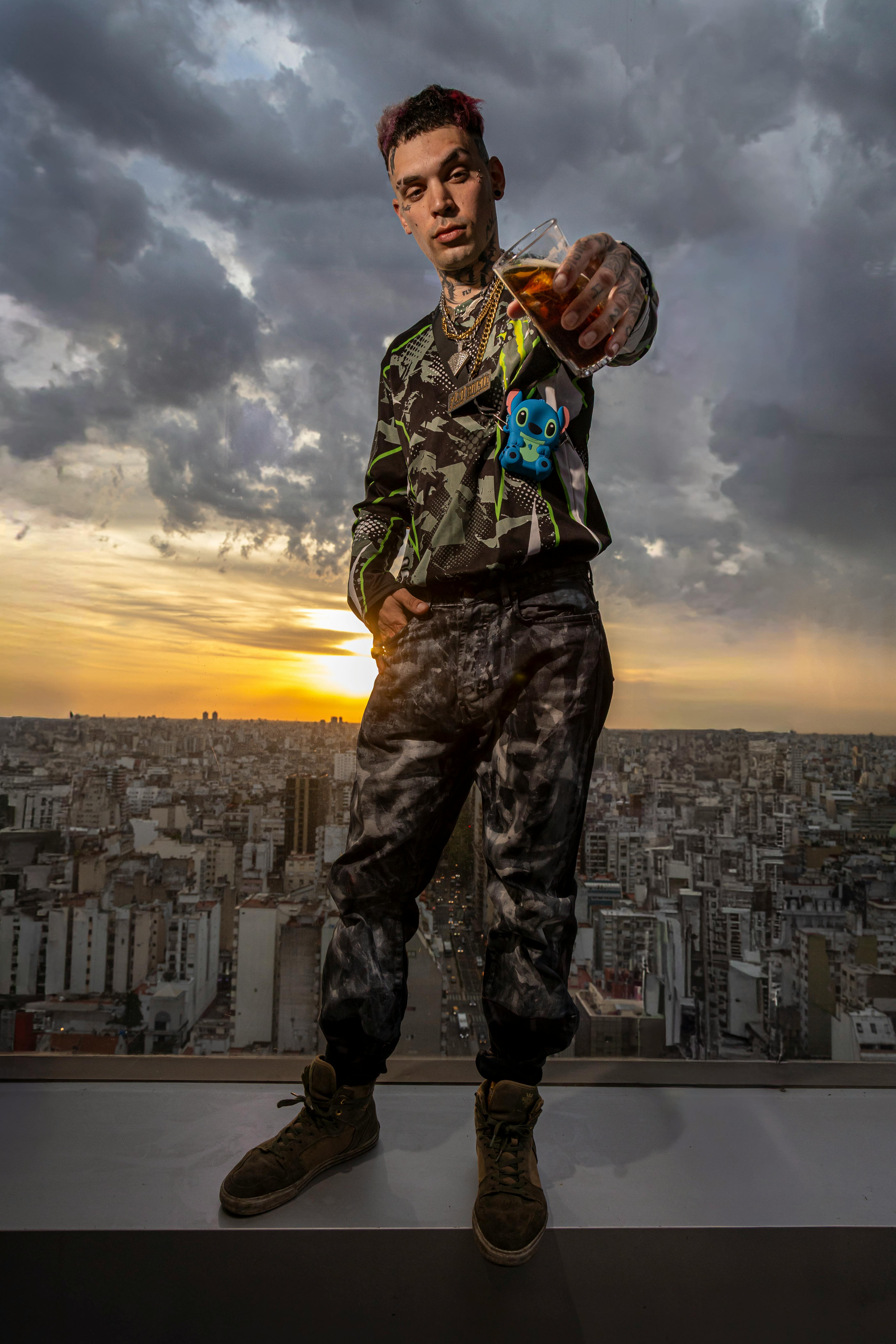 Man enjoying a drink during sunset atop Buenos Aires with cityscape view.
