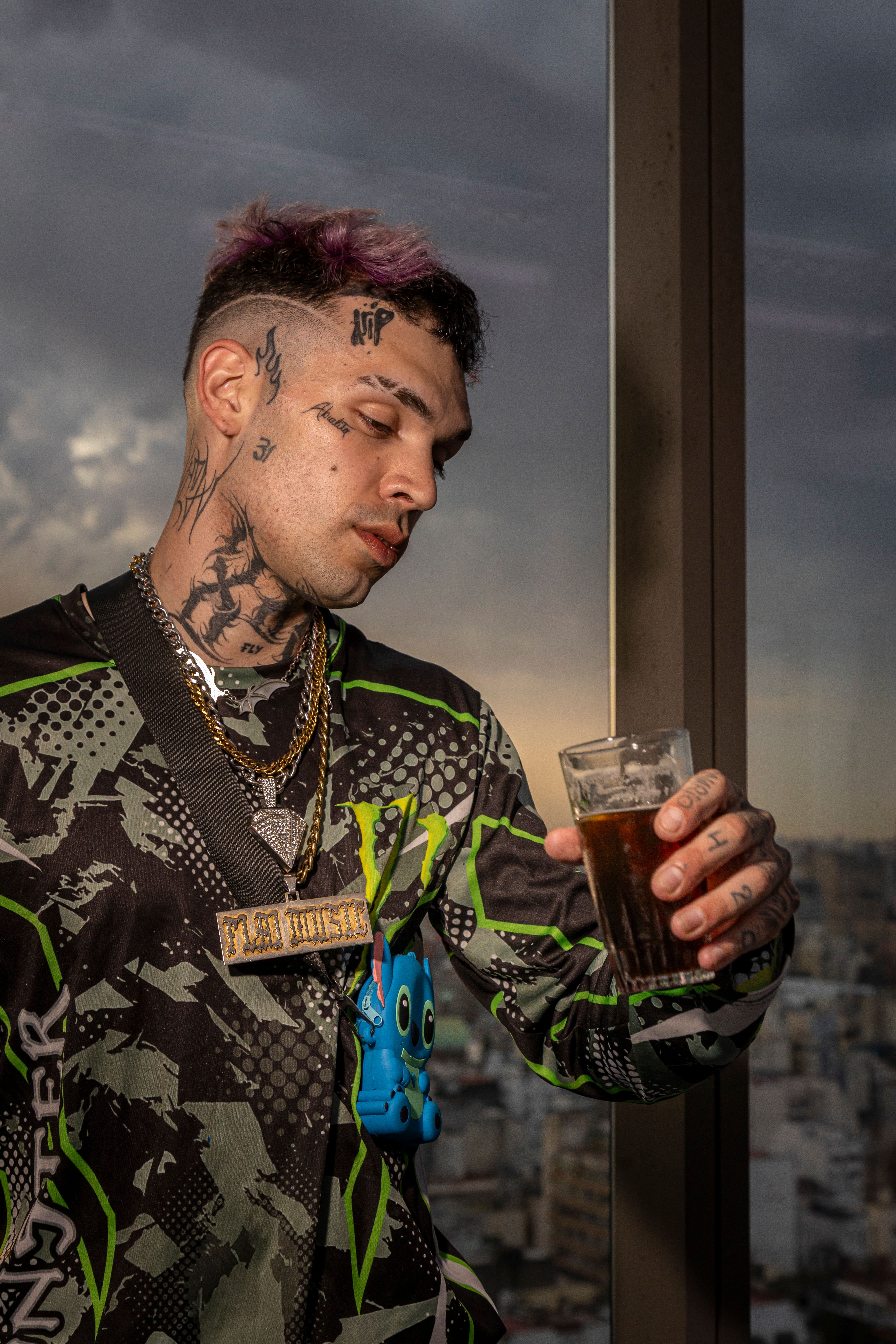 Tattooed man holding a drink, enjoying sunset view in Buenos Aires.