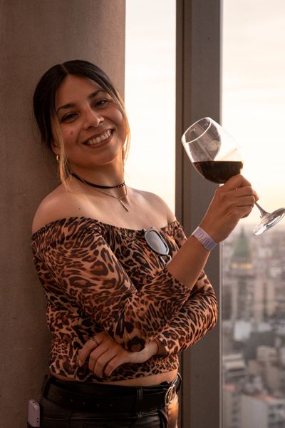 A cheerful woman in a leopard print top holds a glass of wine at sunset in Buenos Aires.