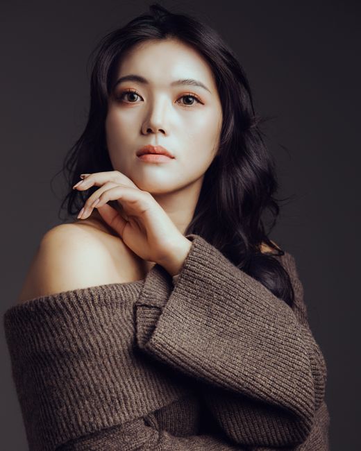 A portrait capturing a woman in a cozy off-shoulder sweater with a calm expression.