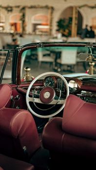 Classic car interior featuring elegant red seats and a timeless steering wheel design in a cafe setting.