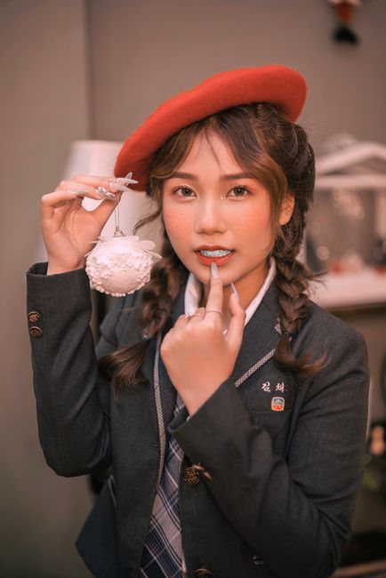 Portrait of a young woman in a red beret holding a decorative ornament indoors, creating a festive atmosphere.