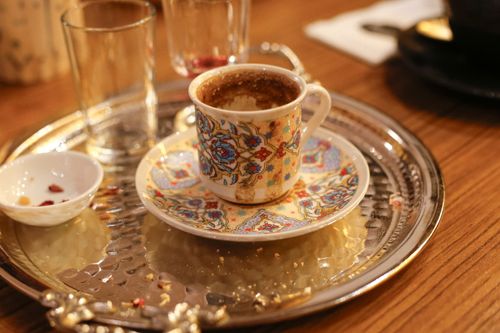 Free Intricately designed cup of Turkish coffee on ornate silver tray, wooden table. Stock Photo
