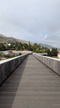 A scenic view of a wooden pathway leading to a lush mountainous landscape on a bright day.