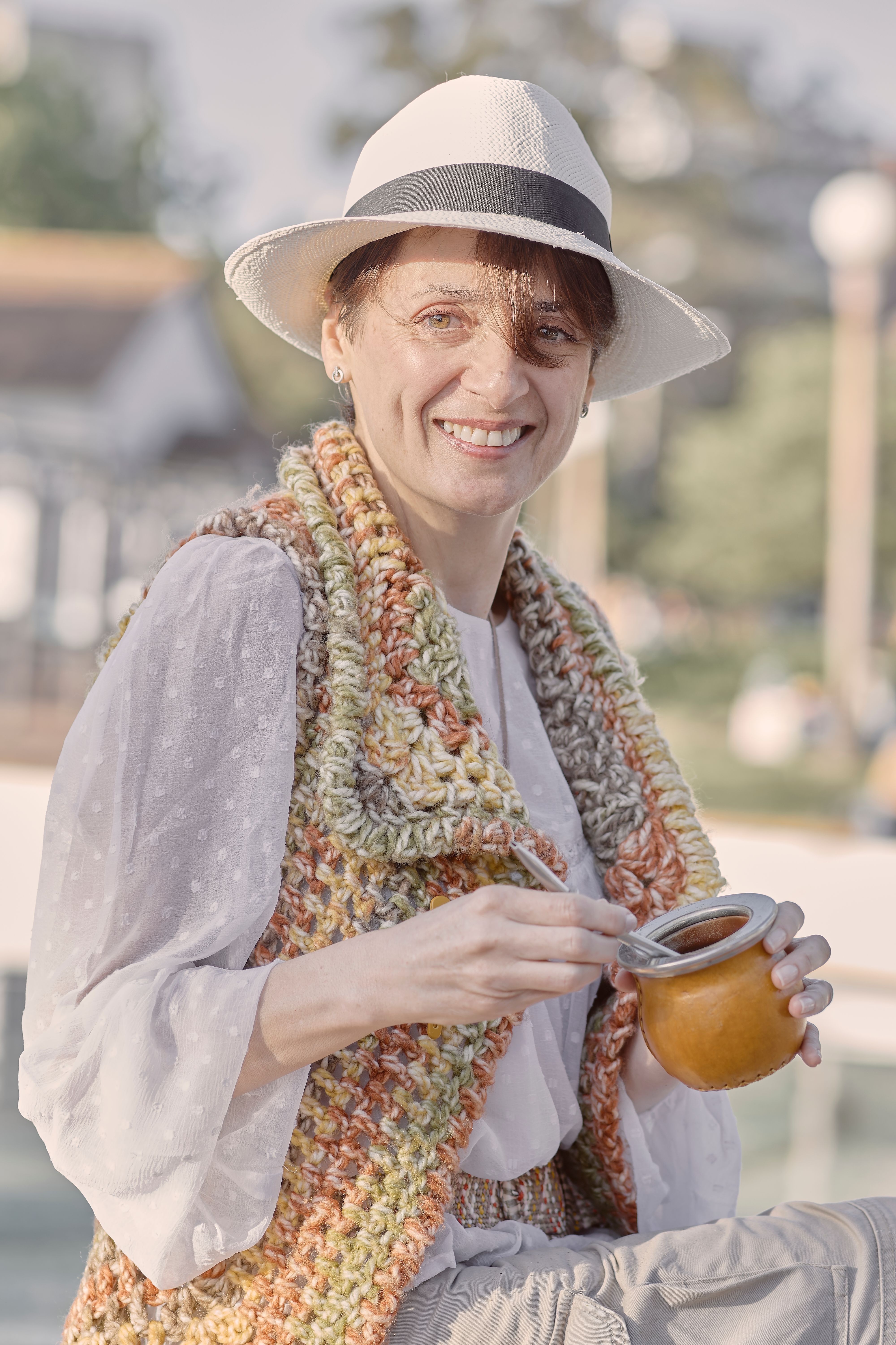 Woman wearing a hat and holding a mate drink outdoors in sunny Montevideo, Uruguay.