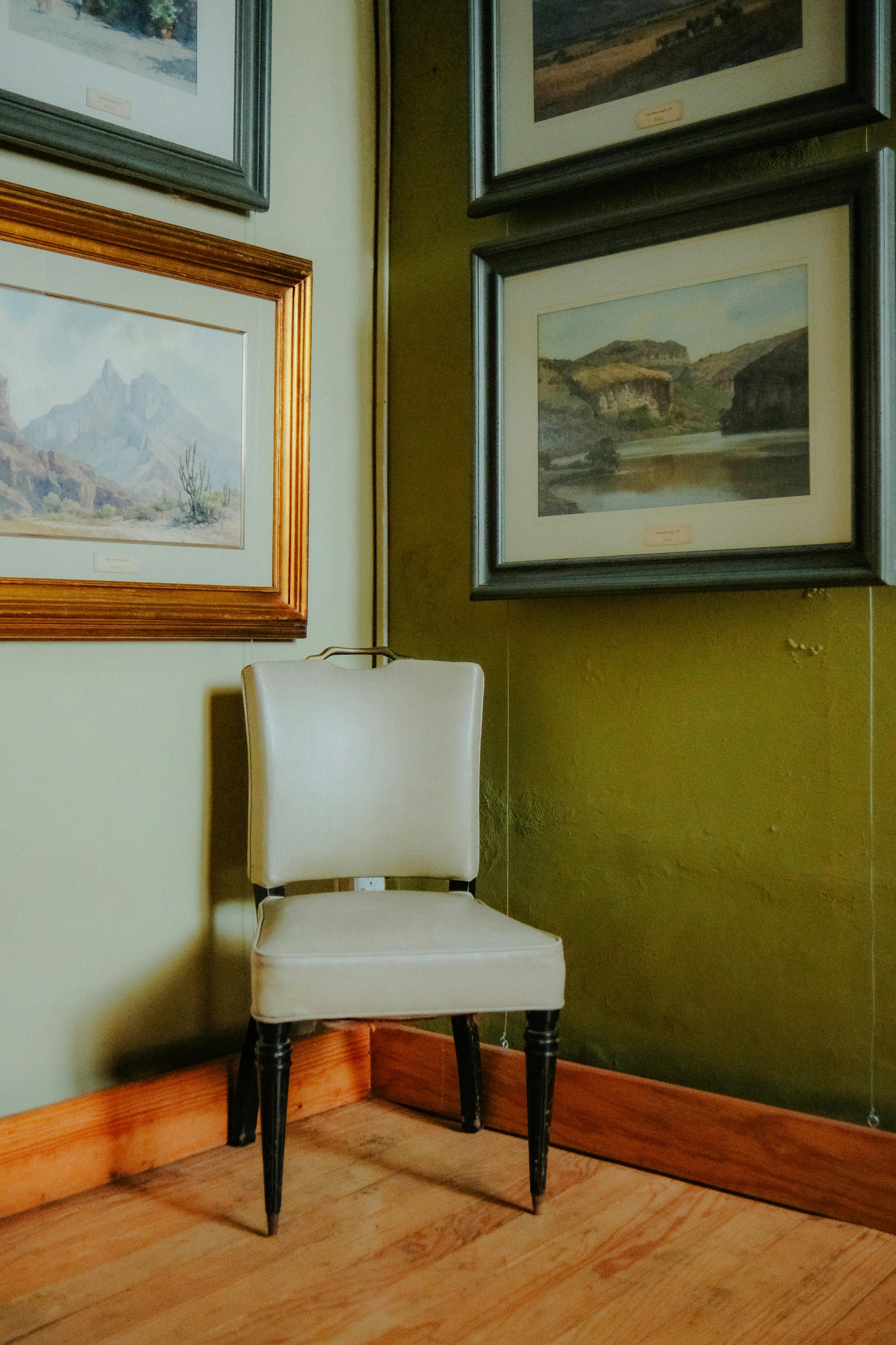 Free Elegant upholstered chair in a cozy corner of a vintage interior, adorned with framed landscape art in Toluca, Mexico. Stock Photo