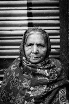 一幅黑白肖像中，一位戴着头巾、表情严肃的老年妇女