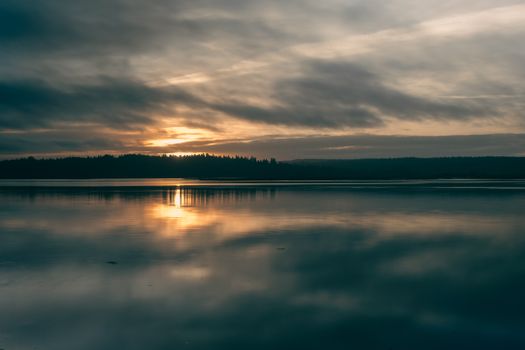 A tranquil dawn view over Puget Sound in Olympia, Washington, with stunning reflections and soft light.