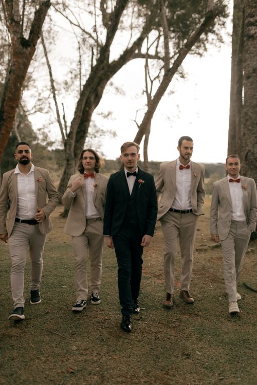 Free Stylish groomsmen in suits walking outdoors in a forest setting. Stock Photo