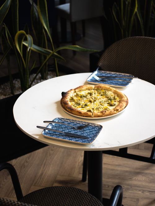 Free A delicious gourmet pizza on a white table with stylish cutlery, perfect for dining indoors. Stock Photo