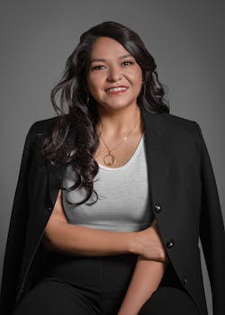 Photo by Zoe Galarza Confident businesswoman in formal attire smiling in a professional studio portrait.