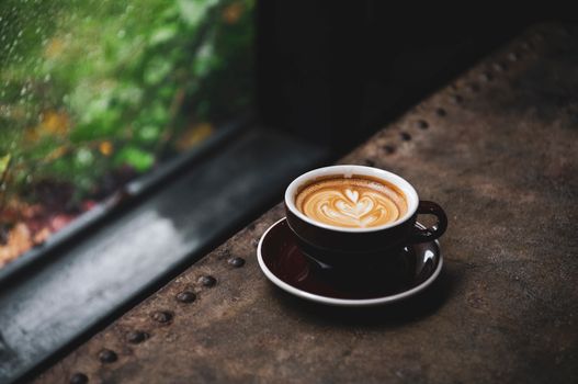 Captivating latte art in a cozy setting near a rainy window, perfect for coffee lovers.