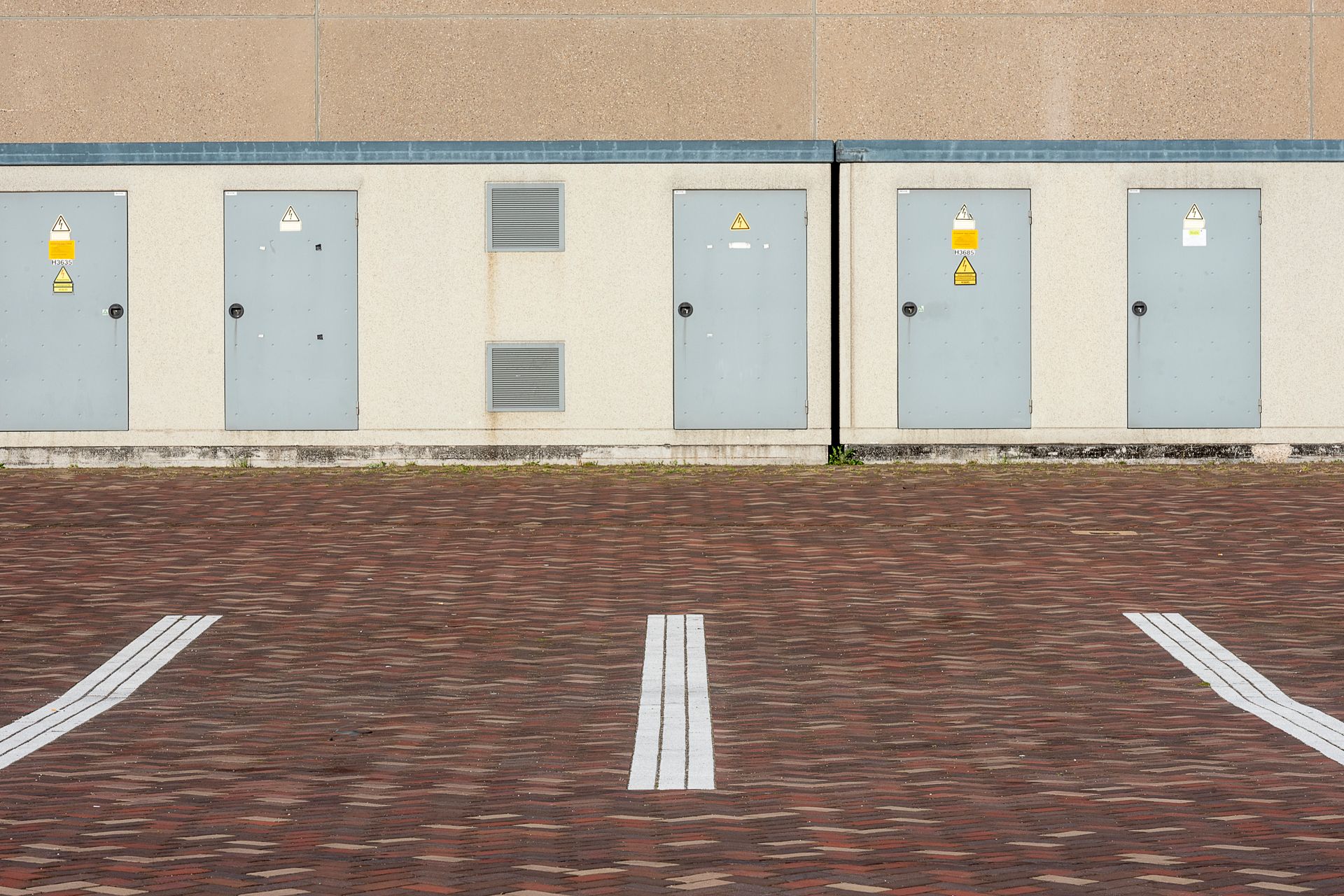 View of an industrial building exterior with parking lines and utility doors.