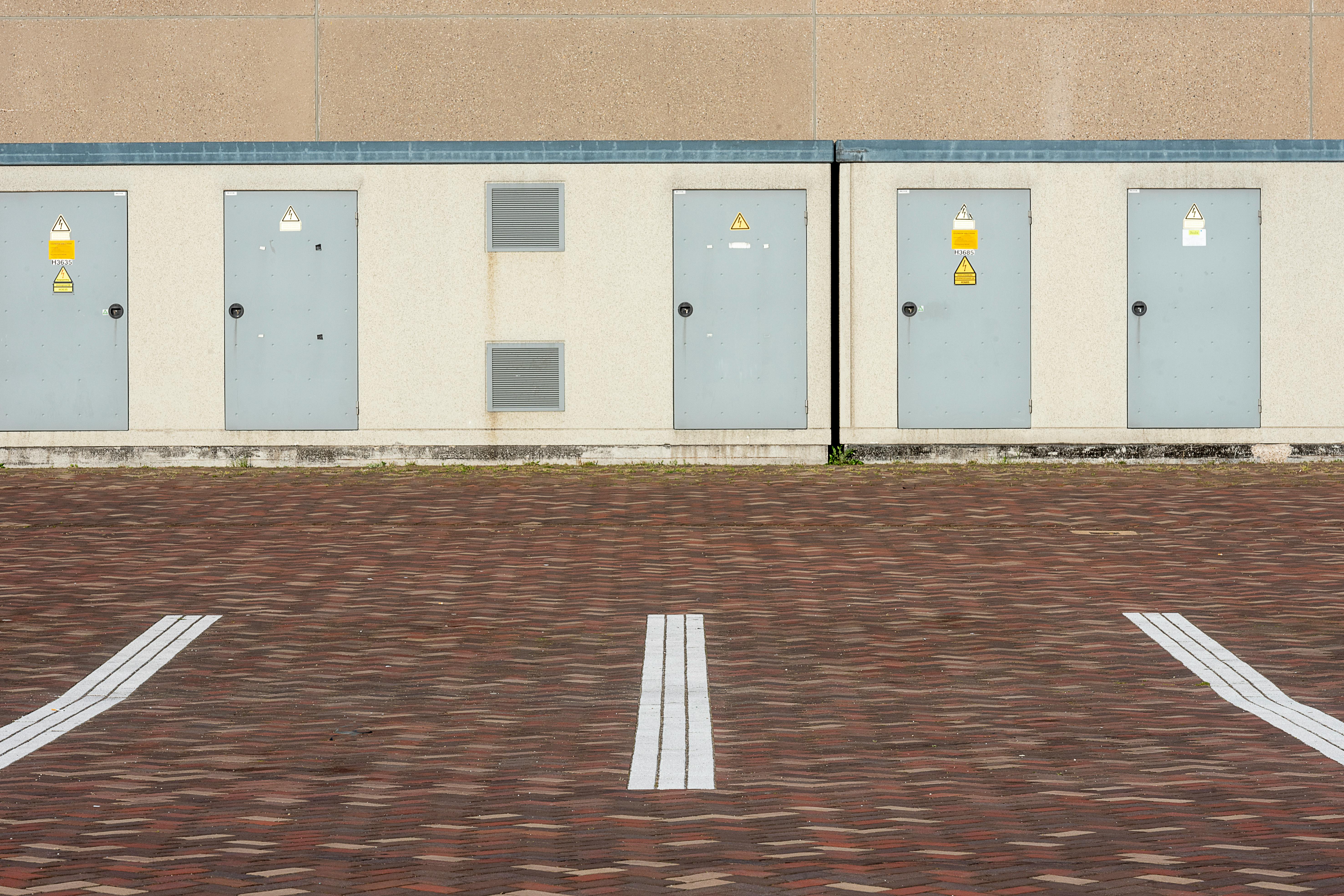 Gratuit Vue de l'extérieur d'un bâtiment industriel avec des lignes de stationnement et des portes utilitaires. Photos