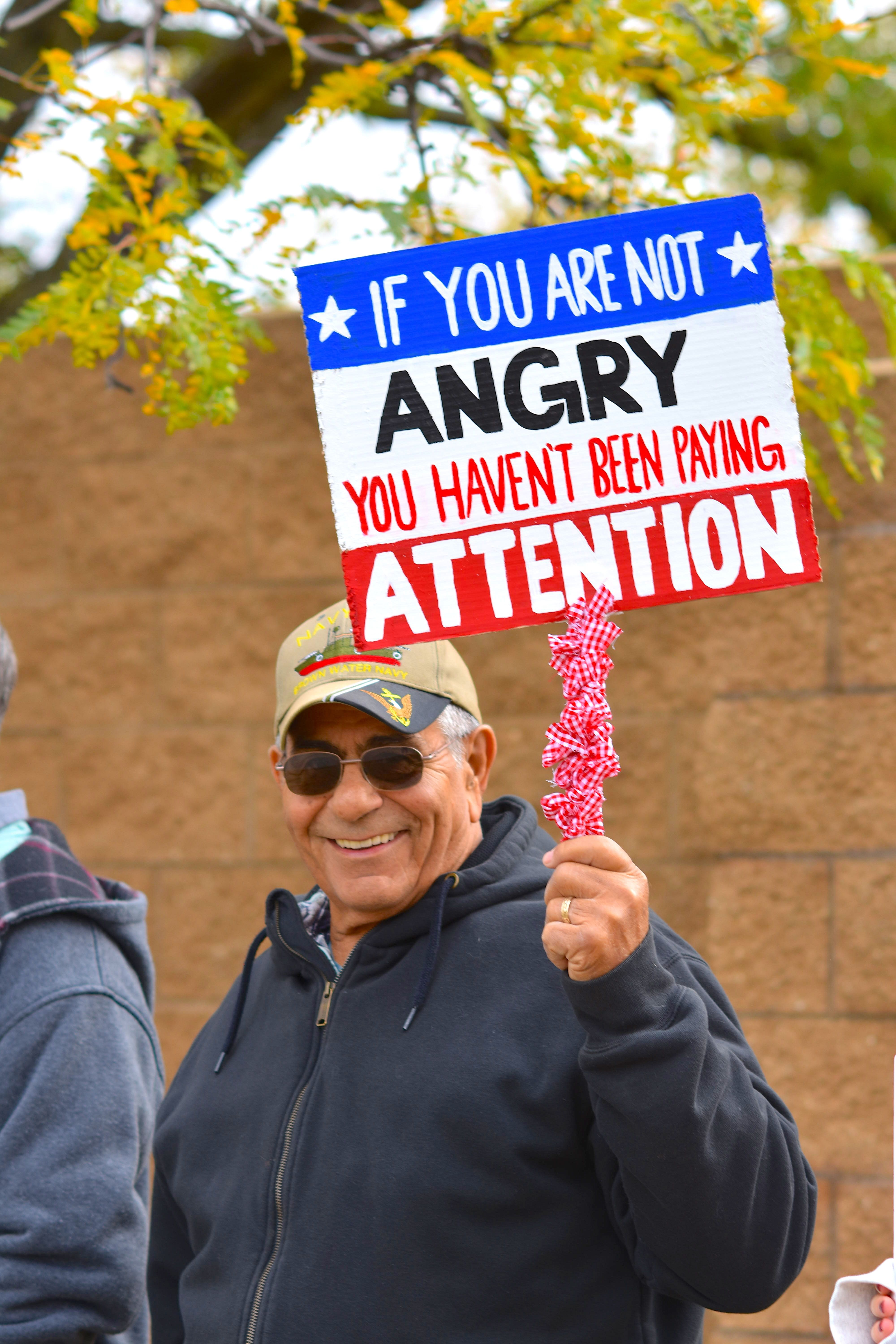 Man Holding Protest Sign at Outdoor Rally · Free Stock Photo