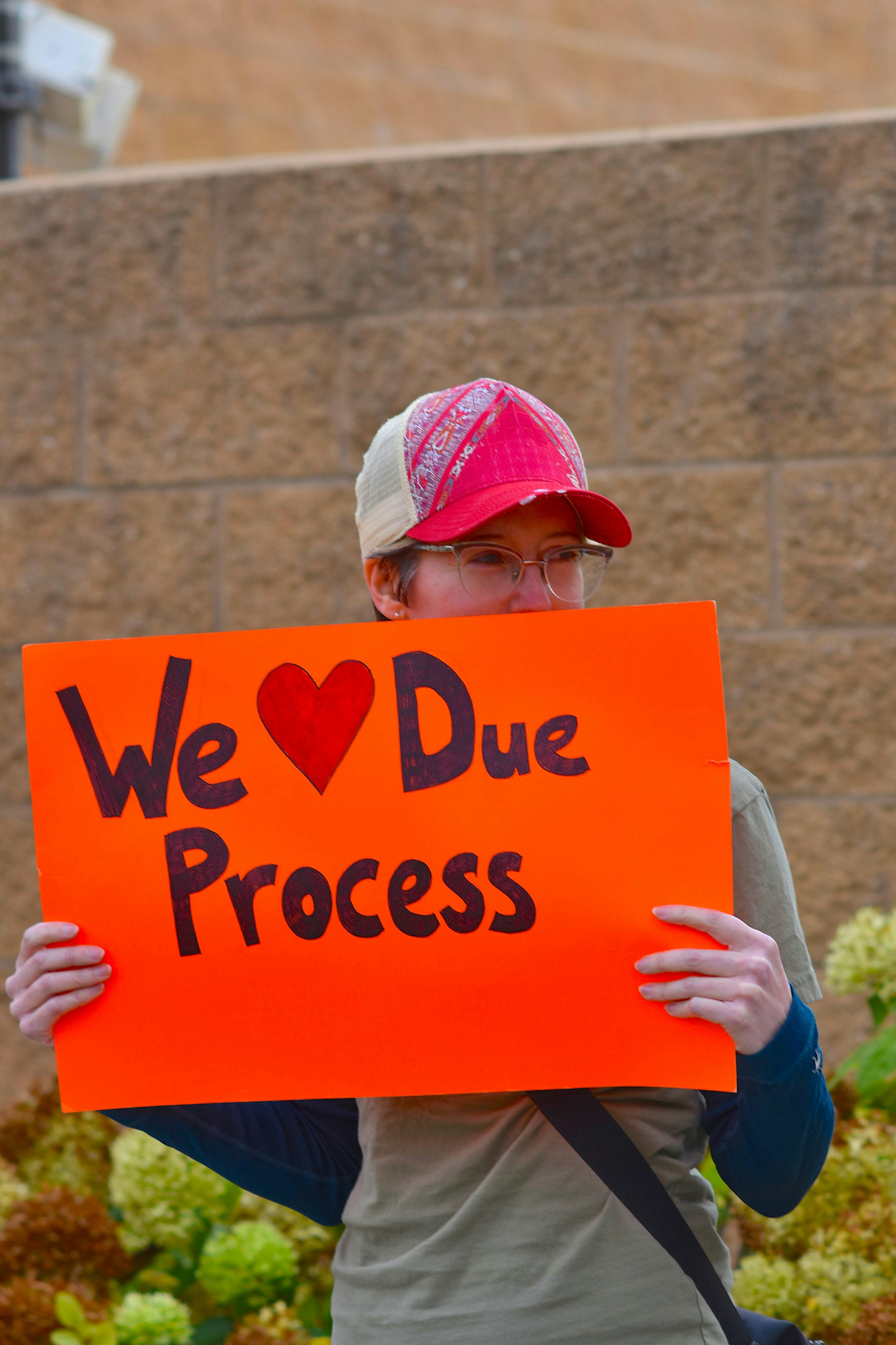 A protester in South Dakota holds a bright orange sign advocating for due process rights.