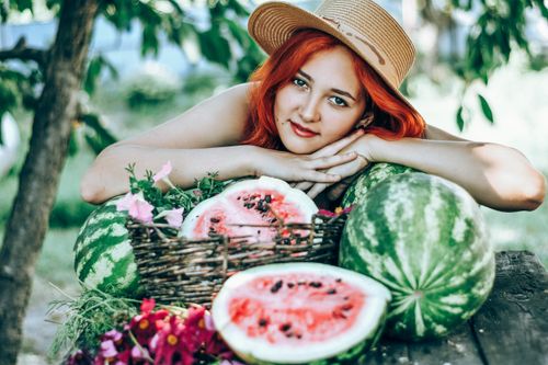 Free Young woman with red hair enjoying summer outdoors with fresh watermelons. Stock Photo