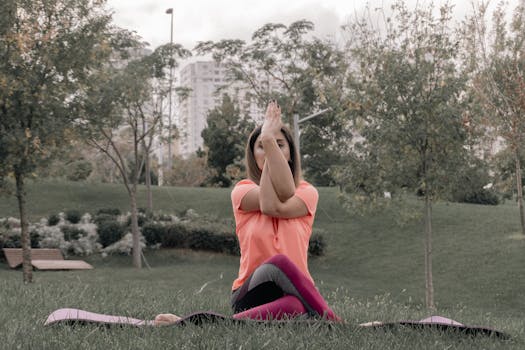 Adult woman performing yoga outdoors in a park. Tranquil setting with greenery and cityscape backdrop.