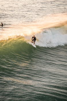 A surfer expertly rides a wave during sunset, showcasing skill and balance in golden light.