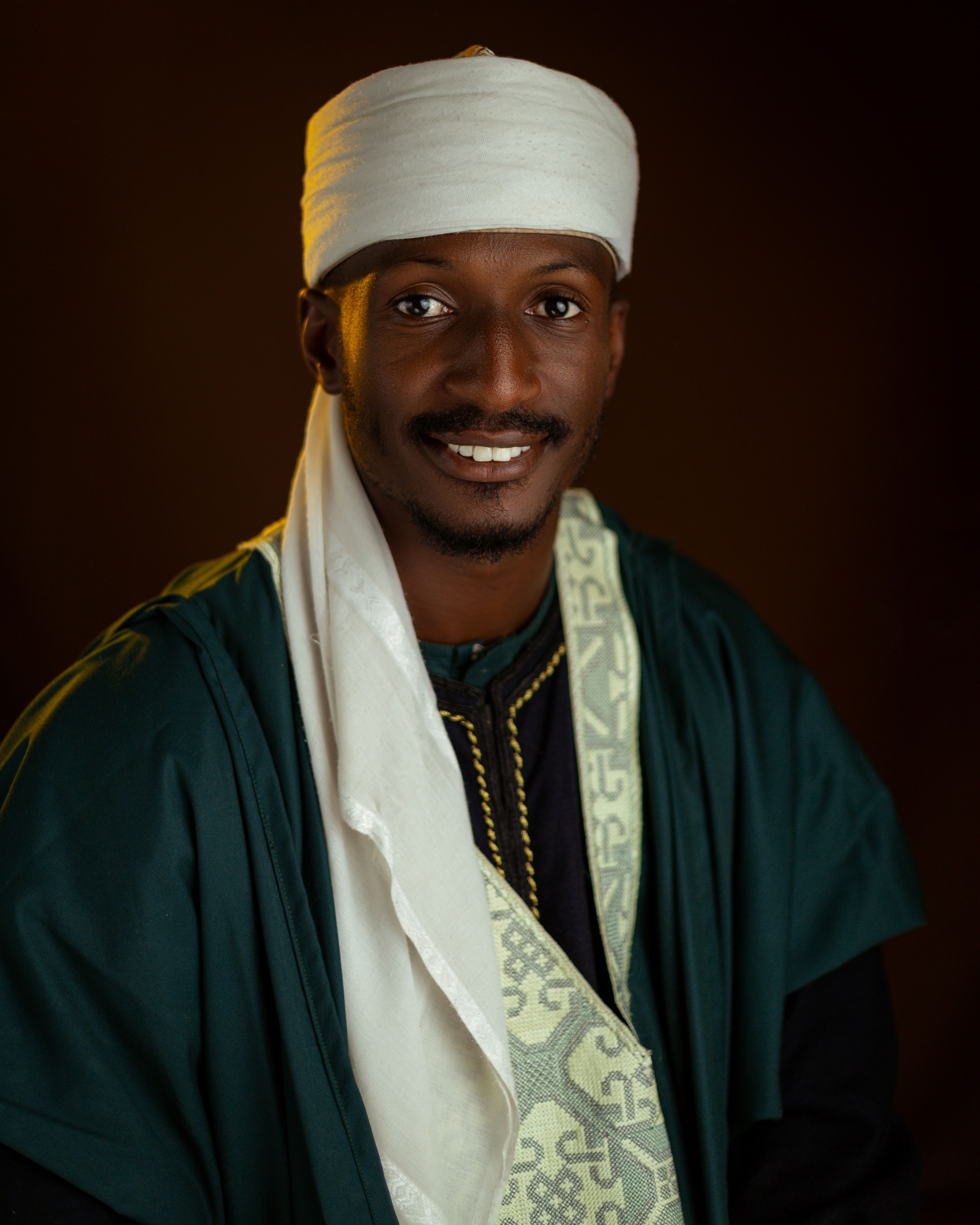 Portrait of a man in vibrant traditional attire with a warm smile.