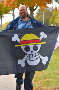 A man in a park holding a pirate-themed flag during a peaceful protest.