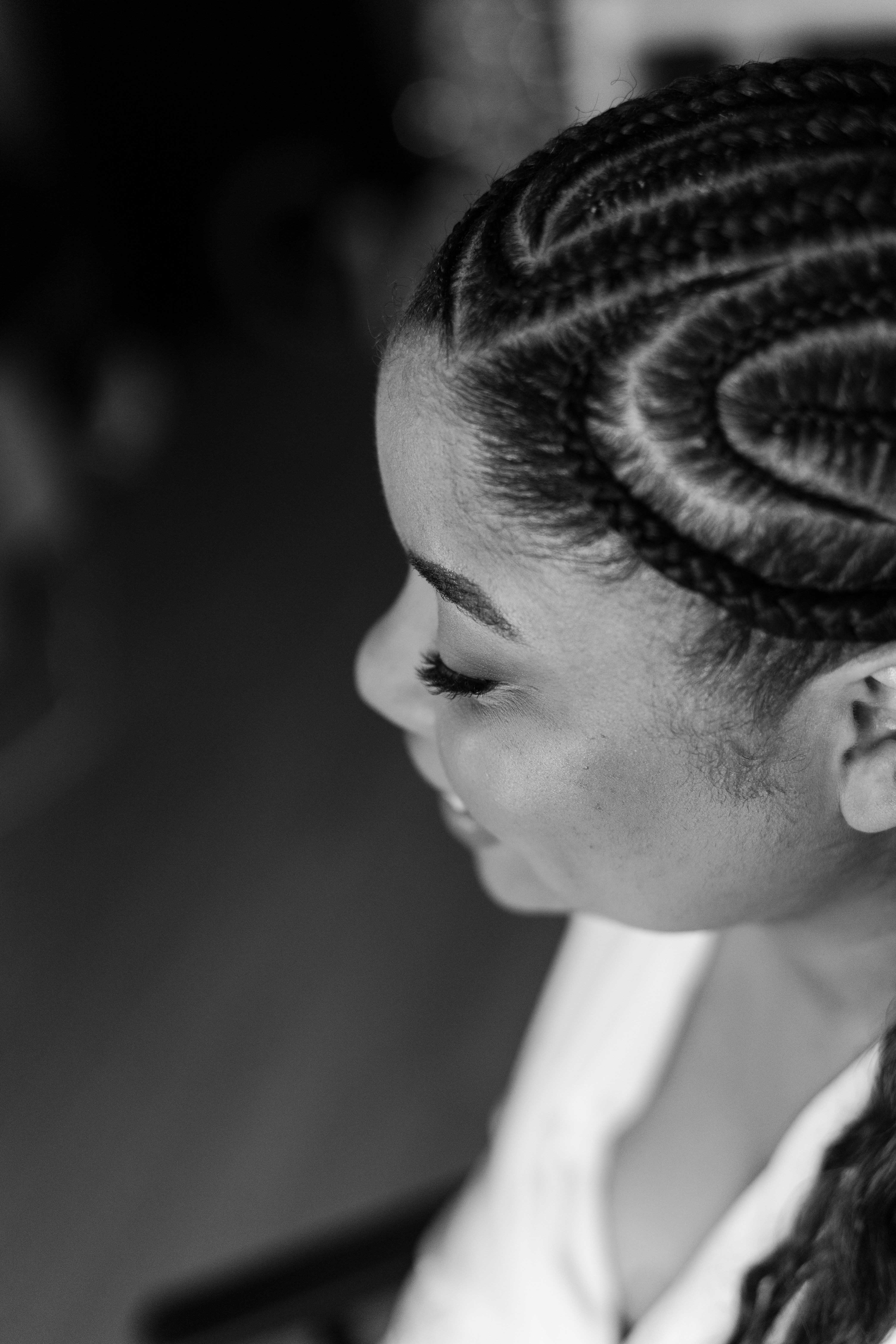 Side profile of a woman with intricate braided hairstyle, captured in a classic black and white portrait.