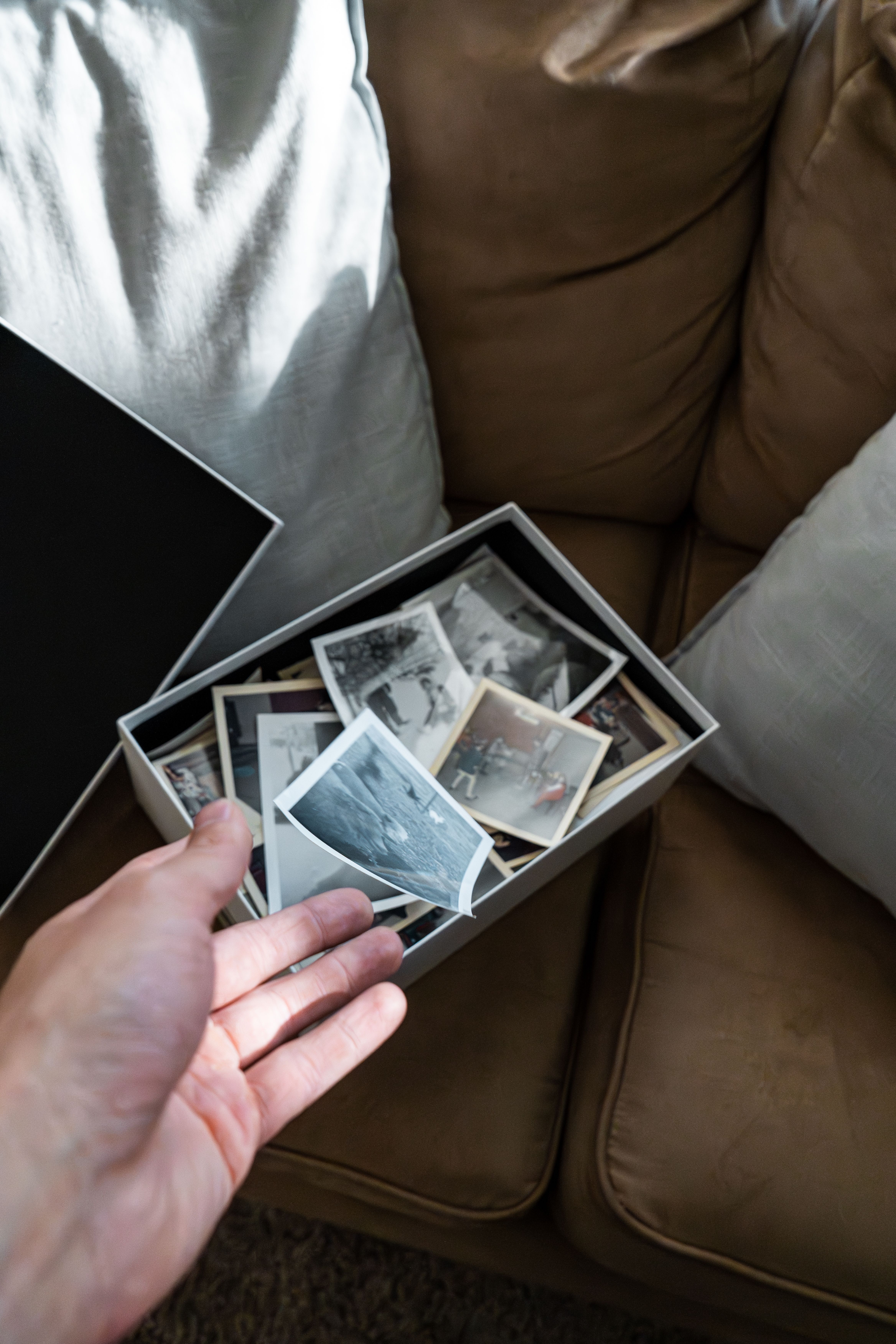 A hand holding vintage family photos in a shoebox, capturing nostalgia.