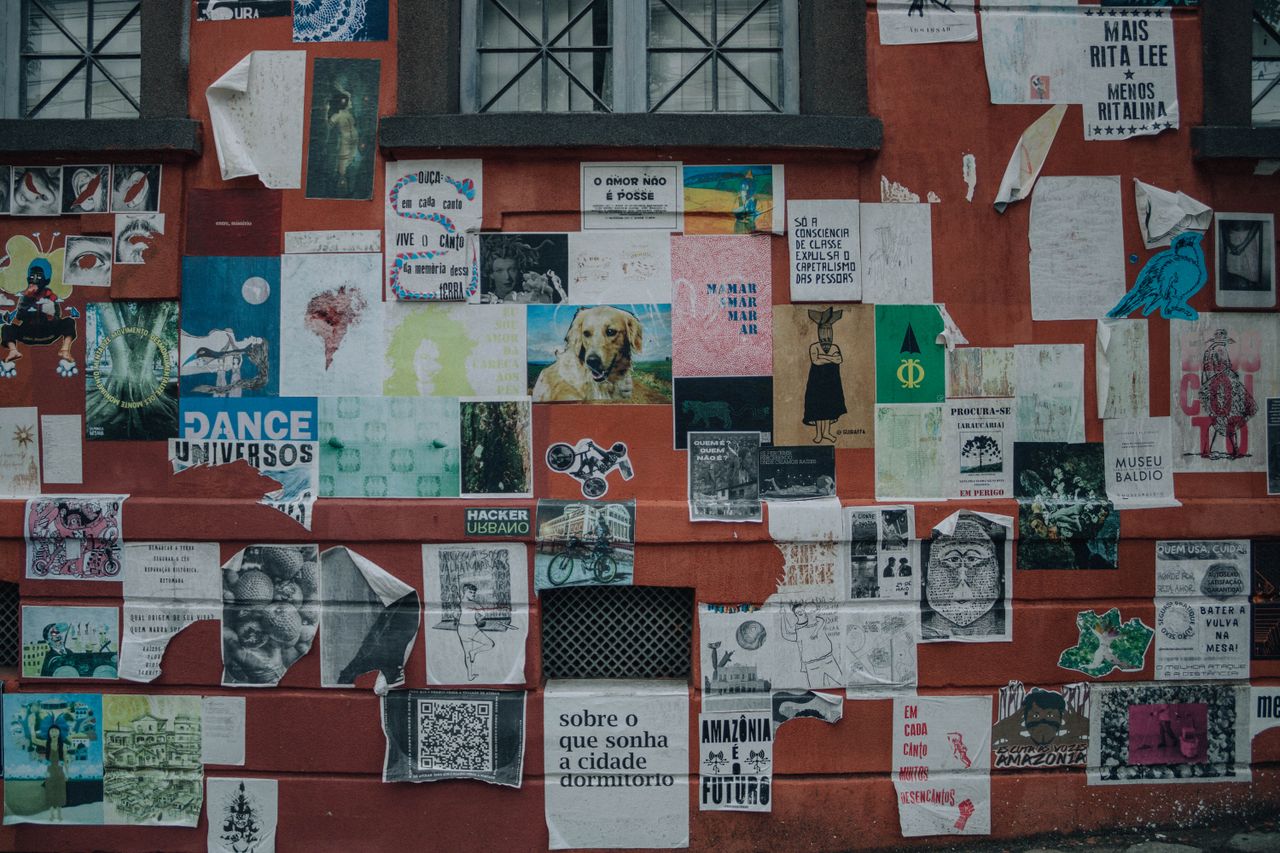 vibrant street art collage on a red wall showcasing diverse posters an