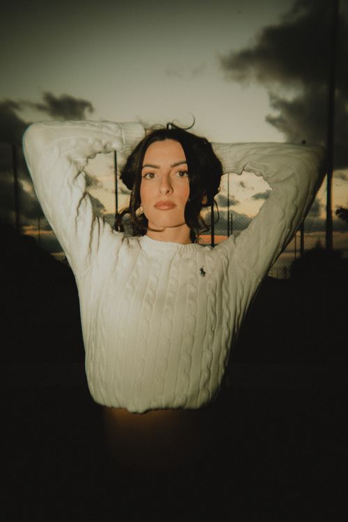 Free Striking portrait of a young woman at sunset, highlighted against a moody sky. Stock Photo