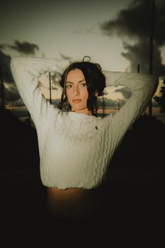 A young woman poses outdoors with a serene sunset backdrop.