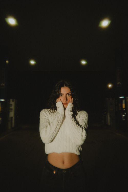 Free Dramatic nighttime portrait of a woman in a white sweater at gas station. Stock Photo