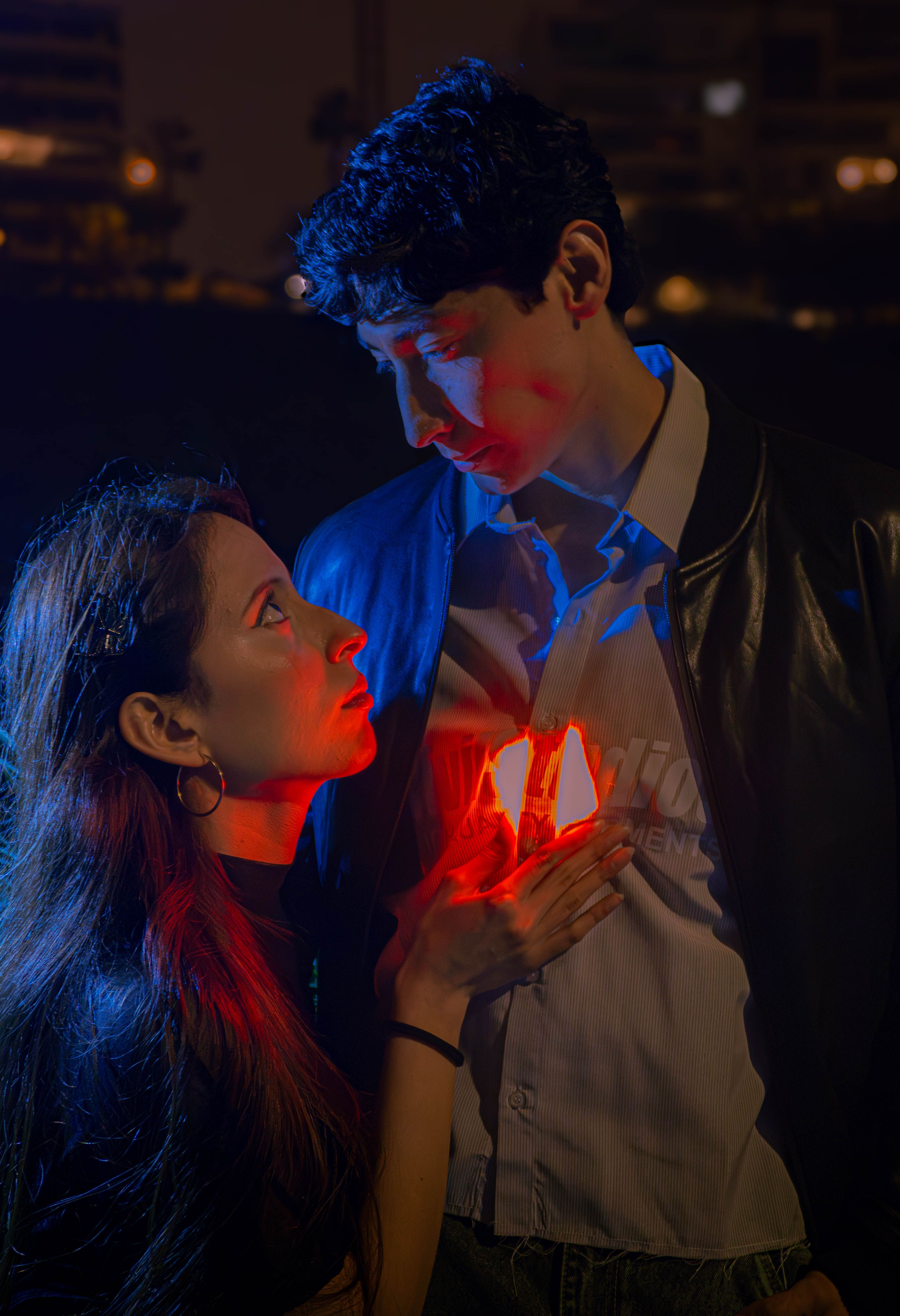 Couple gazing into each other's eyes with vibrant red light glowing between them.