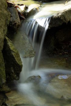 A serene waterfall gently flowing over rocks in a lush nature setting.