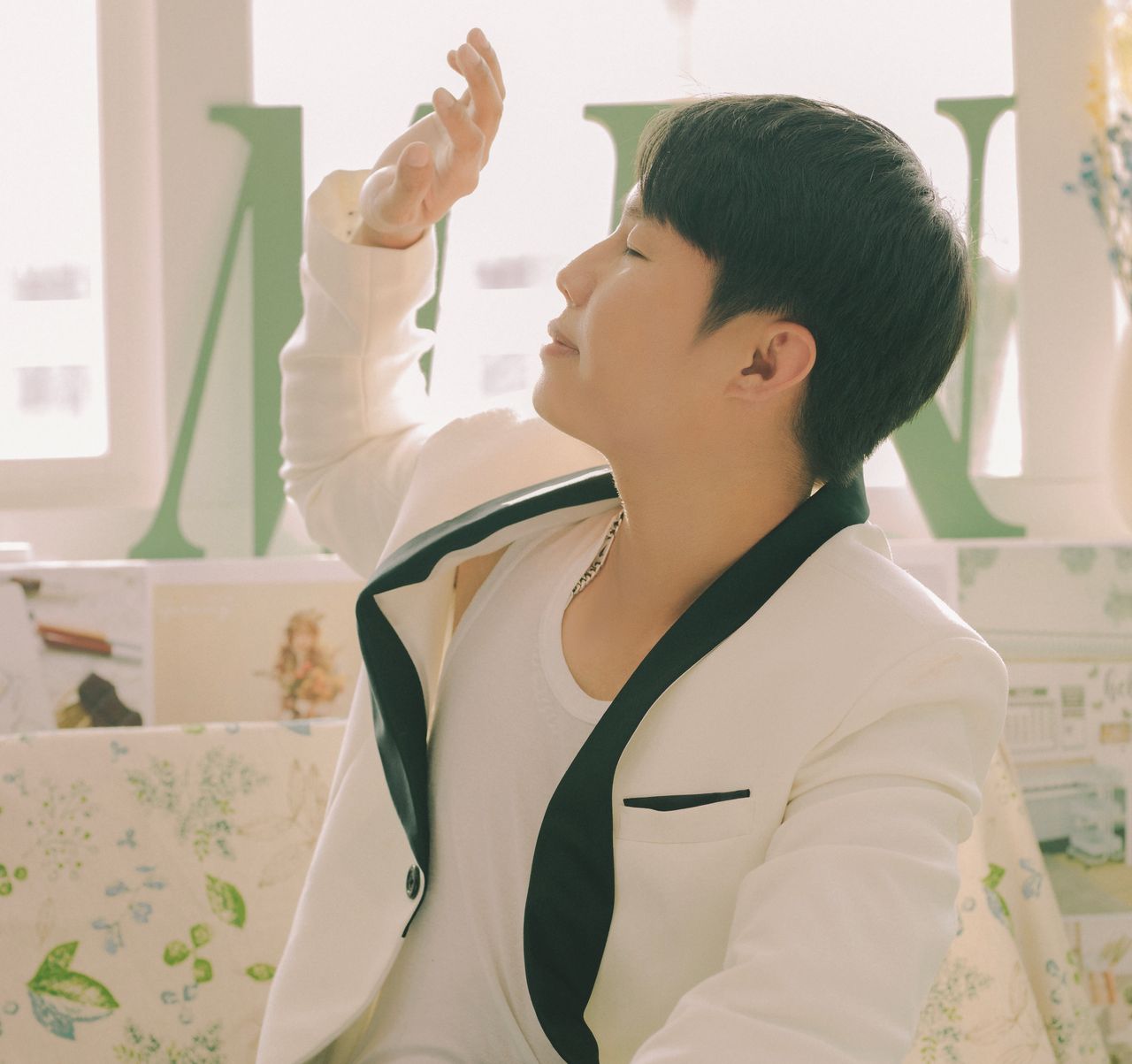 a young man in a chic white blazer enjoys sunlight indoors exuding a r