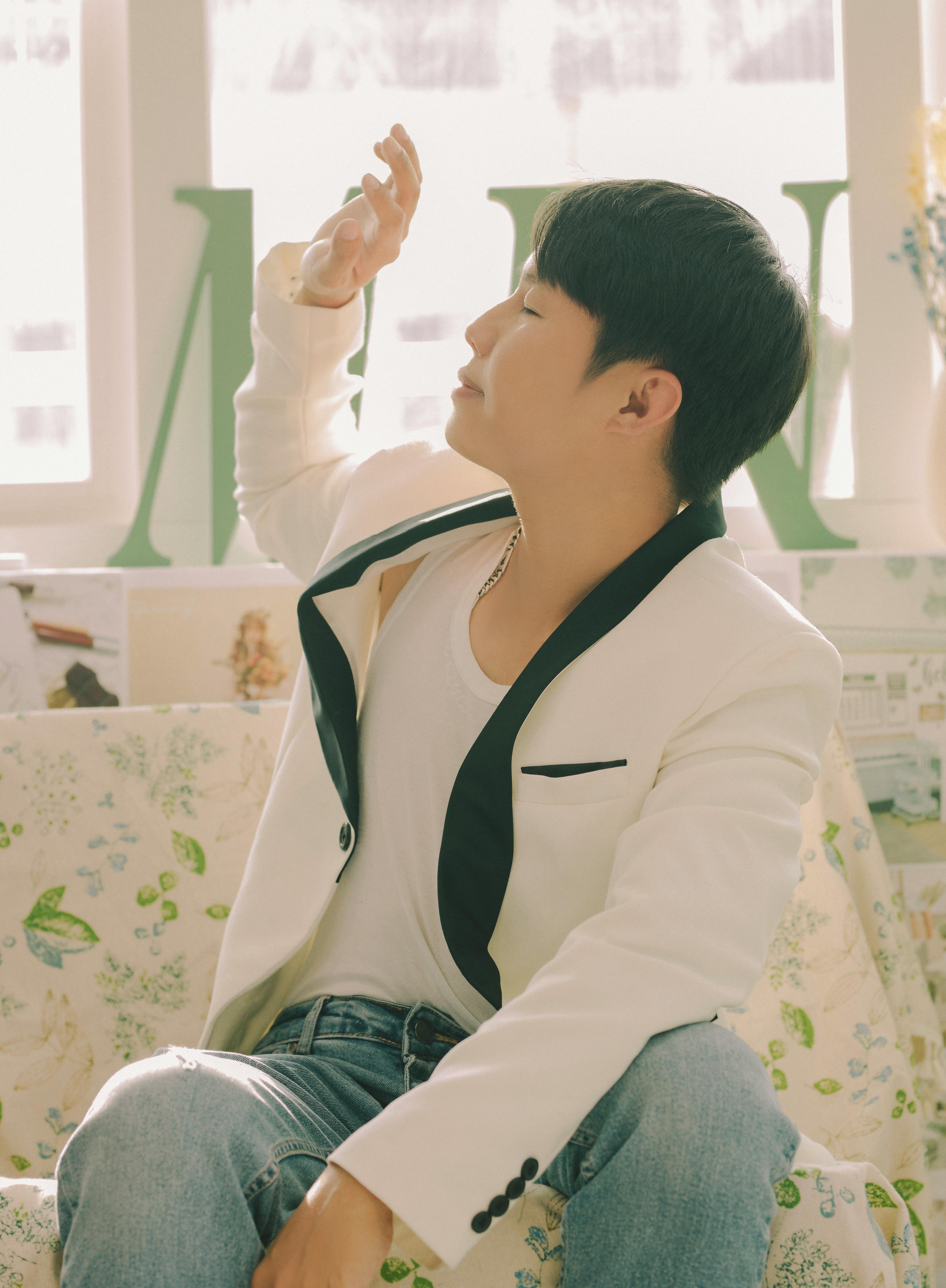 Gratis Un giovane uomo è seduto in un interno, indossa un elegante abito bianco e la luce naturale filtra dalla finestra. Foto a disposizione