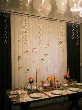 Chic dining table arrangement with balloons and floral decor for a festive indoor celebration.