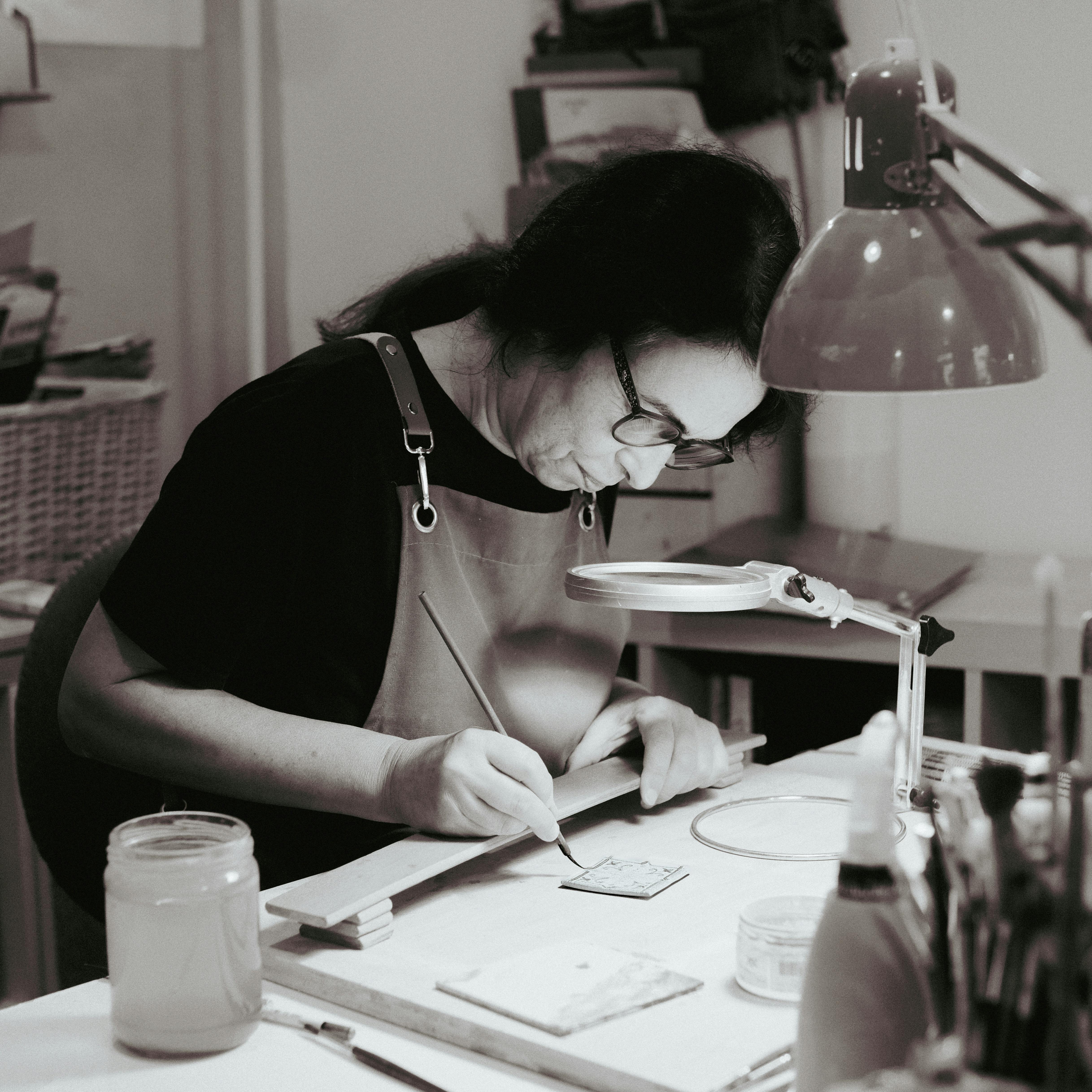 A talented artisan engrossed in ceramic painting at a Lisbon studio, showcasing traditional craftsmanship.