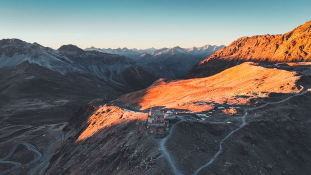 A breathtaking aerial shot of Trentino-Alto Adige mountains at sunset with warm orange hues.