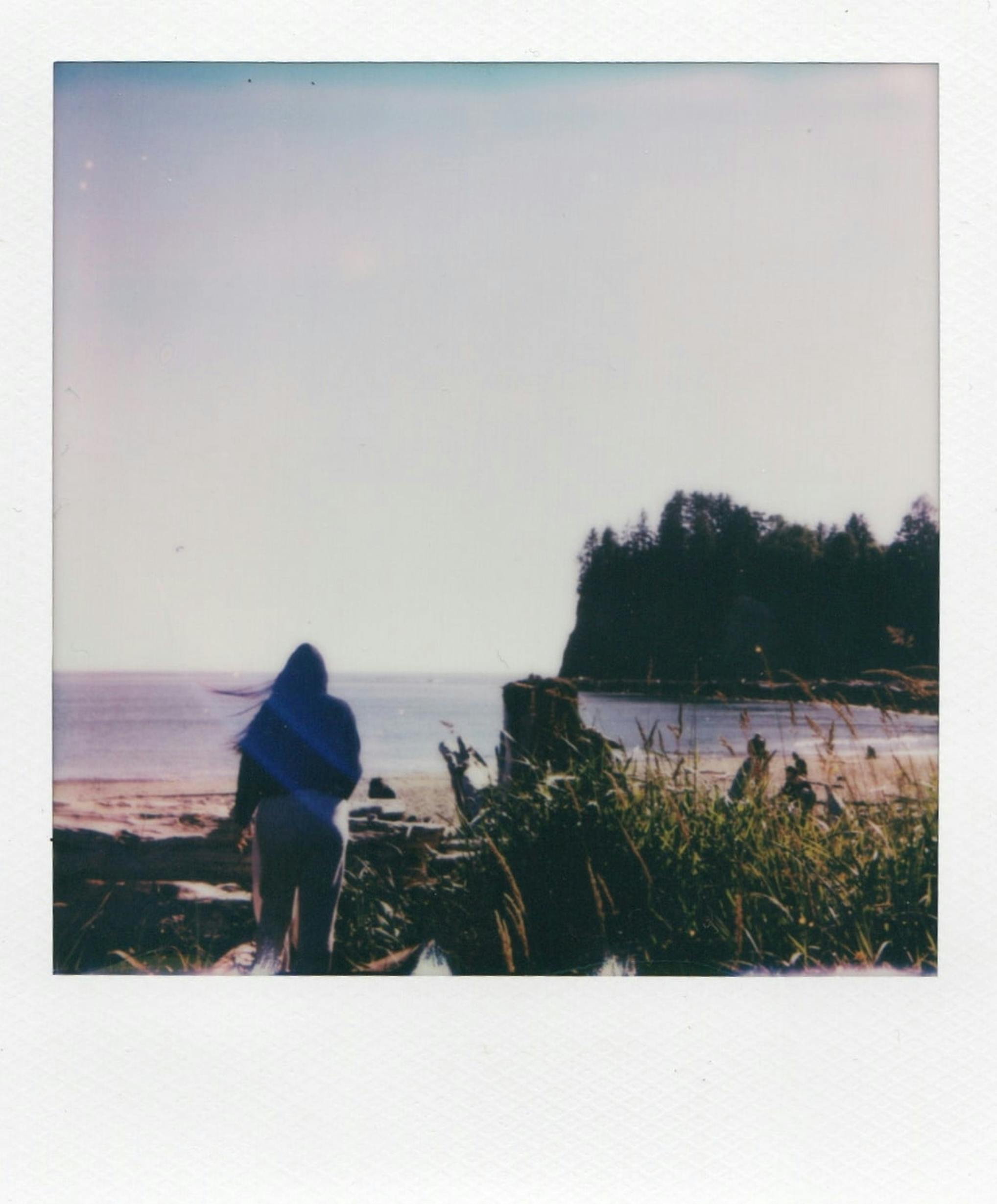 A serene beach view with a person wrapped in a blanket, overlooking the ocean in Forks, Washington.