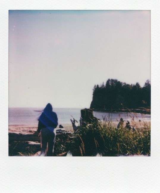 A serene beach view with a person wrapped in a blanket, overlooking the ocean in Forks, Washington.